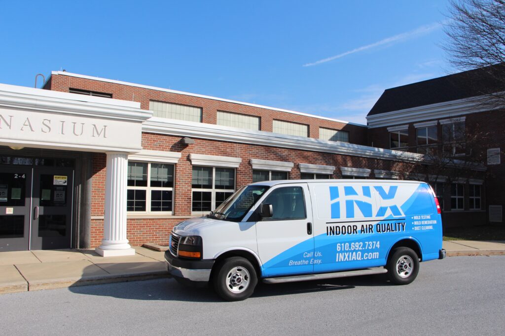 An INX Indoor Air Quality Van parked outside of a commercial client's property