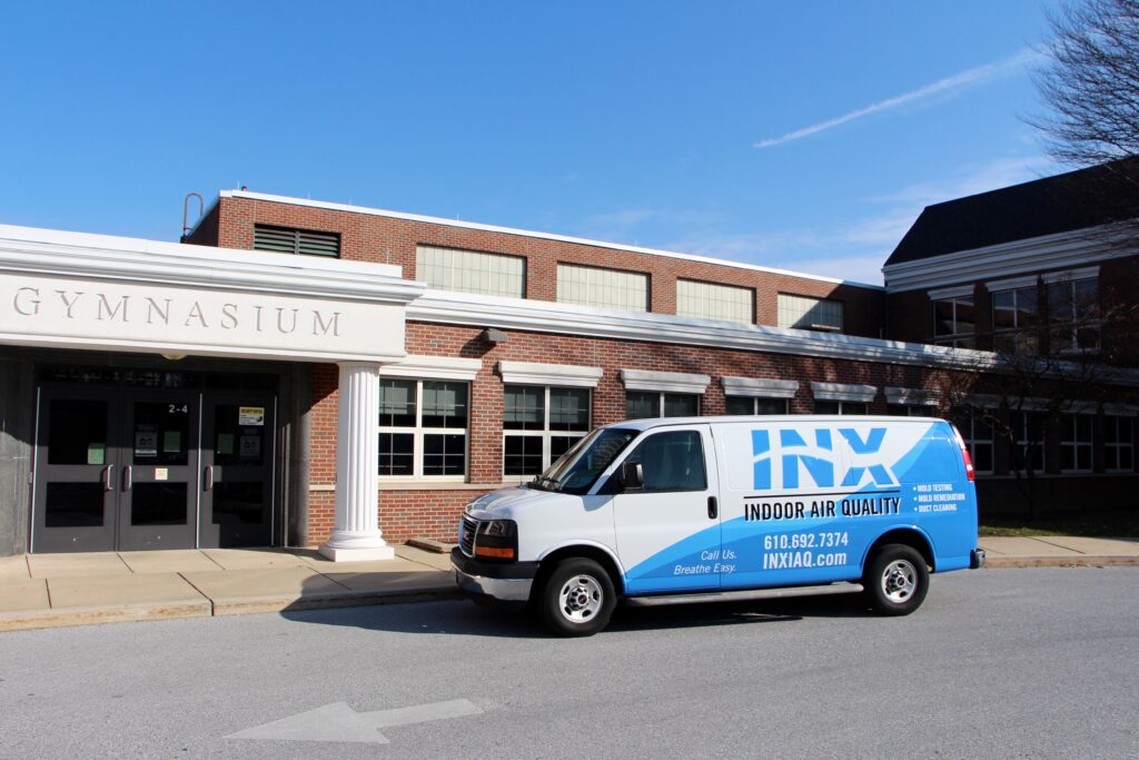 INX Indoor Air Quality van parked outside a gymnasium